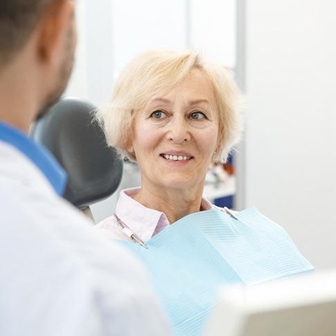 woman smiling while looking at denture